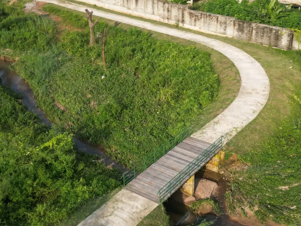 Aerial view of a concrete footpath and bridge over a drainage channel at Maitama Amusement Park