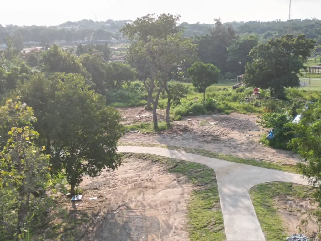 Trees and open ground beside a path in a park in Abuja